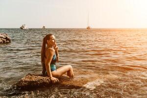 Woman travel summer sea. A happy tourist in a blue bikini enjoying the scenic view of the sea and volcanic mountains while taking pictures to capture the memories of her travel adventure. photo