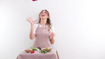 lento movimento pieno HD 240 fps giovane ragazza donna lanciare rosso campana Pepe ridendo cucinando mostrare appetito delizioso verdura insalata vegetariano cibo cucina grembiule e tovaglia uno colore verdure salutare video