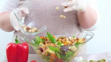 adding nuts to fresh salad vegetarian food almonds hazelnuts cashews aprons close-up only hands delicious diet weight loss healthy lifestyle proteins and carbohydrates red pepper in foreground video