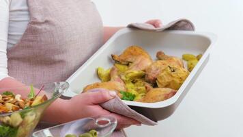 Be H3althy close-up of beige baking sheet potato baked salad woman with large breasts holds and turns baking sheet holds with potholders food appetite advertising space we are the hostess to cook video