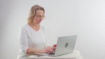 lächelnd blond Frau halten ein Laptop gegen ein Weiß Hintergrund video