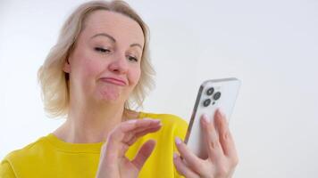 vrouw Holding een mobiel telefoon geïsoleerd Aan wit achtergrond op zoek zijwaarts met twijfelachtig en sceptisch uitdrukking. video
