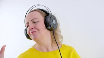 woman dancing in the studio close-up face and hands waving hands in front of the screen on a white background pleasure joy enjoyment big professional headphones bright clothes video