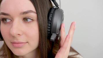 Smiling caucasian young woman listening to the podcast e-book music song singer rock band in headphones earphones, choosing sound track on cellphone isolated in white background video