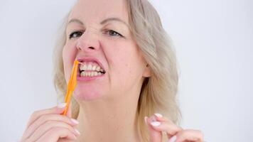 meia idade Loiras mulher goza entre uma escova de dente escovar dentes escovar sujeira levando Cuidado do ela mesma odontologia mulher bonita sorridente mostrando gostar depois de comendo dental Cuidado video