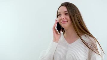Smiling thousand-year-old woman talking on the phone at home, happy young girl holding a cell phone answering a call, an attractive teenager pleasantly talking on a cell phone with a friend video