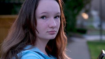 portrait de une magnifique Jeune fille à la recherche dans le caméra et souriant. une charmant femme habillé dans une luxueux est permanent sur le rue. video