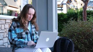 Busy attractive girl working at the laptop as sitting on grass in city park on hectic summer morning, outdoor shot in urban area video