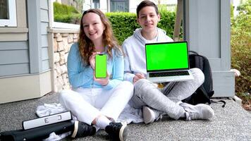 teen boy and teenage girl sitting outdoors with folders backpack holding laptop and phone green screen chroma key ad look here school presentation on computer kid ready for lesson. teen laptop. video