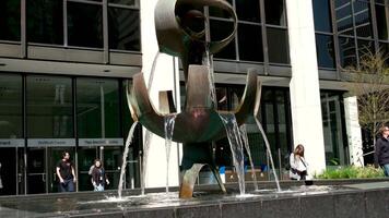 Fontain of the pioneers Burrard street against the backdrop of building We work sculpture by artist George Tsutakawa falling water flowing down from a strange bowl waterfall fountain of Vancouver city video