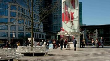 Canada Place People walking buying tickets for a tourist trip around the city on bicycles buses and ships ticket office white benches spring bare trees cold sunny video