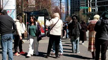 mensen zijn staand Bij de trolleybus hou op aan het wachten voor openbaar vervoer in de stad van Vancouver verschillend paren jong Dames mannen weinig jongens wandelen Verleden de camera voorjaar koel warm jassen video