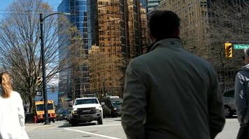 incrocio stradale nel vancouver persone attraversare il strada macchine di diverso nazionalità guidare persone nel maschere e senza primavera un' lotto di bianca macchine contro il fondale di grattacieli e spoglio alberi video