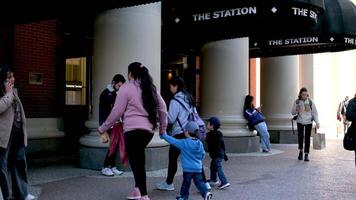 zwei Mütter von anders Nationalitäten mit Kinder eingeben das Skytrain Bahnhof Center von Vancouver andere Menschen bestehen durch ein Frau mit ein Telefon nähert sich das Kamera stoppt suchen zum ein Weg video