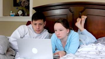 Two friends using laptop together on a bed in living room video