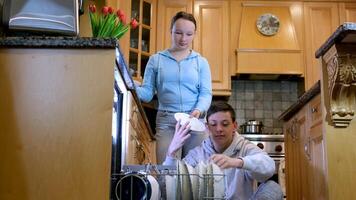 posare su piatti a partire dal lavastoviglie adolescente ragazzi ragazza Aiuto genitori a casa lavori di casa lavori di casa cucinando lavare pulito vicino lavastoviglie nuovo tecnologie bambini siamo a casa distribuzione di domestico obblighi video