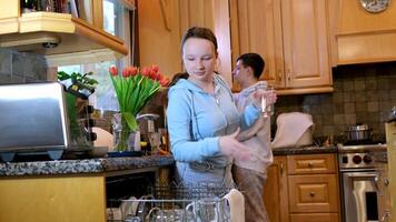 House chores concept.Housewife taking out clean plates from dishwasher machine. Female hands unloading dishwasher close up. Modern technologies for home video