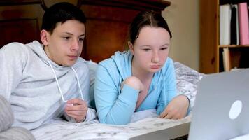 tieners in de kamer in de buurt de computer kijk maar een film samen besteden tijd eerste datum mooi zo verhouding bloemen liggen in de slaapkamer Aan de bed zitten aangenaam atmosfeer schoolkinderen Doen huiswerk samen video