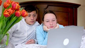 adolescentes en el habitación cerca el computadora reloj un película juntos gastar hora primero fecha bueno relación flores mentira en el dormitorio en el cama sentar agradable atmósfera Niños de escuela hacer deberes juntos video