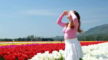 collection of videos and photos where a girl in a white skirt walks through field with tulips blue background sky mountains bright flowering fields teenager young woman walk outdoors beauty self-care