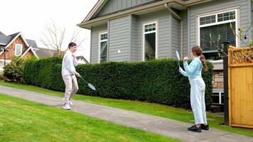 children teenagers boys girl playing badminton outdoors on street against cherry blossoms rest relaxation spring summer spend nice time having fun playing sports games friends classmates school age video