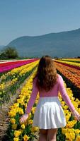 collection of videos and photos where a girl in a white skirt walks through field with tulips blue background sky mountains bright flowering fields teenager young woman walk outdoors beauty self-care