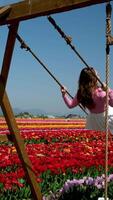 A girl playing in a flower garden ride on a swing hair develops pink blouse of a European girl white skirt video