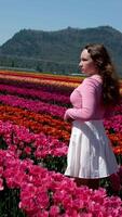 Little cute girl with long curly hair wearing a light pink skirt walks between whites and pinks hyacinthus in beautiful colorful hyacinth field in the netherlands video