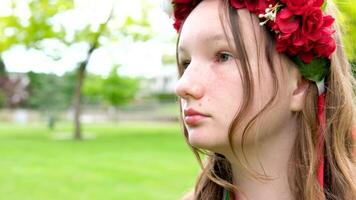 skön ukrainska ung kvinna anbud flicka i en stor röd krans av ljus rosa vit röd blommor flätning band i hår vind ömhet renlighet fred i ukraina fredstid människor verklig liv video