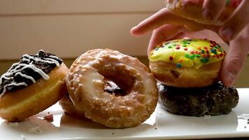 delicioso dulce fragante rosquillas estar en un blanco plato cerca el ventana manos tomar y rehacer el imagen dulce dañar a salud calorías amor para azúcar video