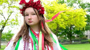 mooi oekraïens jong vrouw inschrijving meisje in een groot rood krans van helder roze wit rood bloemen vlechten linten in haar- wind tederheid netheid vrede in Oekraïne vredestijd mensen echt leven video