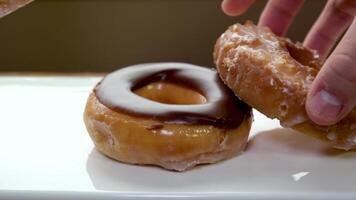 two hands put delicious donuts on a white plate three different Donuts with holes pink chocolate and glazed close-up offer menu tasting dessert large selection advertising video