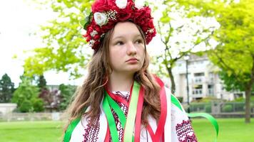 mooi vrouw met een krans Aan een groen weide oekraïens meisje met een krans van bloemen video