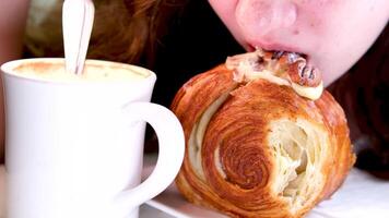 Porträt von genießen Mädchen beißen Dessert beim Zuhause im schleppend Bewegung. Nahansicht zufrieden Frau suchen beim Kamera mit schick Kuchen im Hand. attraktiv Brünette Mädchen Essen Kuchen im Zuhause Küche. video