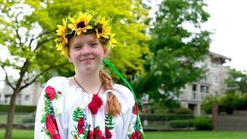 mooi roodharig oekraïens meisje in een geborduurd blouse bloemen rood klaprozen Aan een wit overhemd zonnebloemen krans in haar- linten natuur Oekraïne patriottisme nationaal kleding is komt eraan in mode video