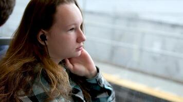 une femme qui regards en dehors le fenêtre et écoute à le la musique sur le écouteurs dans une en mouvement train video