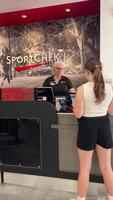 SportChek joyful teenage girl standing at cash register smiling and buying herself a new cap shopping emotions expensive cool sports brands shopping malls pastime for young girls and women Canada 2023 video