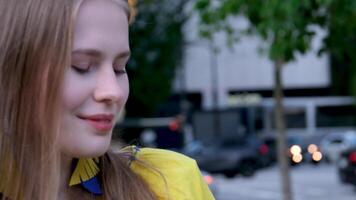 beautiful cute girl slow motion closeup face blue eyes pink lips in the big city yellow blue clothes tender smile slow motion camera pulls up from behind moving cars and skyscrapers video