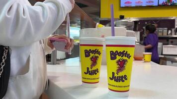 booster juice a little girl a teenager a teenager straw inserts it pierces her glass of a bright drink and drinks it tasted delicious good brands of juice a trip with friends two glasses canada 2023 video