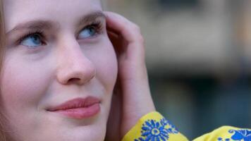 vrede in Oekraïne mooi echt Dames geel overhemd met blauw bloemen borduurwerk mooi jong meisje vrouw glimlachen looks in de kader blauw ogen oekraïens vlag van Oekraïne in de kleur van kleren video