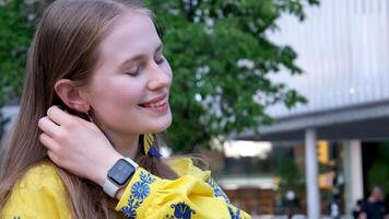 The girl is wearing an embroidered shirt, national Ukrainian Slavicclothes, a yellow shirt. straighten hair with hands long dangling earrings in blue and yellow embroidery blue flowers video