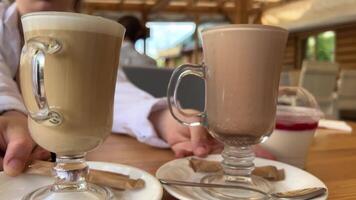 två glas koppar på tabell med varm drycker kakao och latte jämförelse av Färg och smak flicka ändring platser på vit plattor utsökt mat tjänande Nästa till plast behållare gelé Kafé på gata video