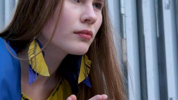 Frau mit ukrainisch Flagge auf Schultern betet Hände gefaltet im Vorderseite von Truhe blond Haar zärtlich Schönheit Jugend Schmerzen im Herz Krieg im Land Ukraine werden Sieg Erwartung Gebet Anfrage zu Gott ich wollen Frieden video