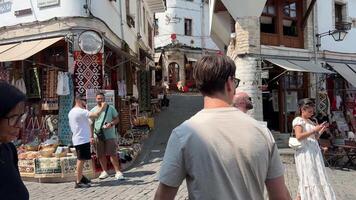 moderno vida en el turístico antiguo pueblo de hipocrasta personas turistas caminando a lo largo el estrecho calles Roca losas en el suelo resbaladizo losas pavimentado pavimento muchos personas video