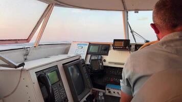 in captain's cabin of ship, young girl windshield to steer steering wheel dawn to cross to island of Corfus city of Saranta Albania driver captain adult man behind the wheel hold the steering wheel video