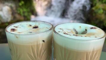 zwei Brille auf das Hintergrund von ein Wasserfall das Zoomen aus von vereist Cappuccino mit Kaffee Bohnen und Kekse video