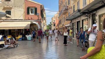 limitar ruas alta amarelo edifícios em a ilha do Corfu turistas caminhando por aí a cidade ímãs venda vida é dentro cheio balanço dentro uma turista cidade céu alta edifícios Grécia video