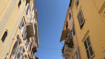 versmallen straten hoog geel gebouwen Aan de eiland van corfu toeristen wandelen in de omgeving van de stad magneten uitverkoop leven is in vol schommel in een toerist stad lucht hoog gebouwen Griekenland video