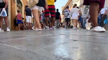 legs of people crowd of tourists walking on the island of Corfu central street in the city paved tiles on the ground unrecognizable people tourists space for text travel Greece video
