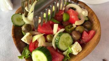 met twee vorken hij mengsels de salade met genoeg van tomaten Aan de bord tussen de groenten, specerijen en oliën zijn gemengd zo dat ze zijn gelijkmatig gedistribueerd video